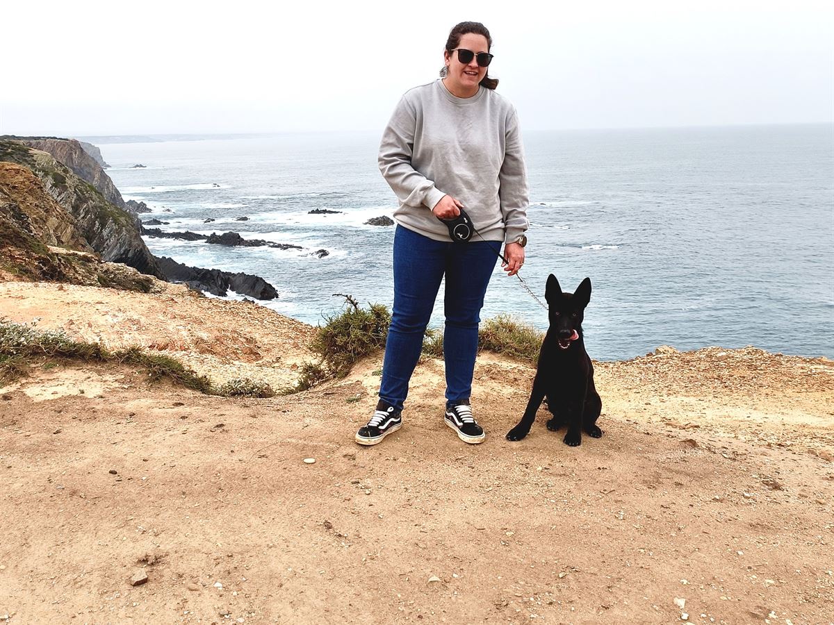 Debbie Sterrenberg, home care lead at SilverCoast Paws & Home, photographed on a Silver Coast clifftop with a client's black Belgian Shepherd