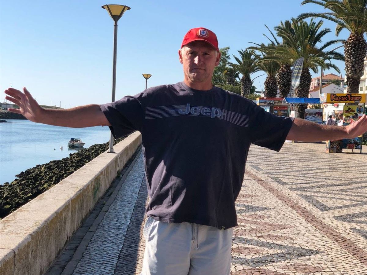 Michael Straub, master craftsman at SilverCoast Paws & Home, photographed with arms wide on a Portuguese tiled promenade on the Silver Coast