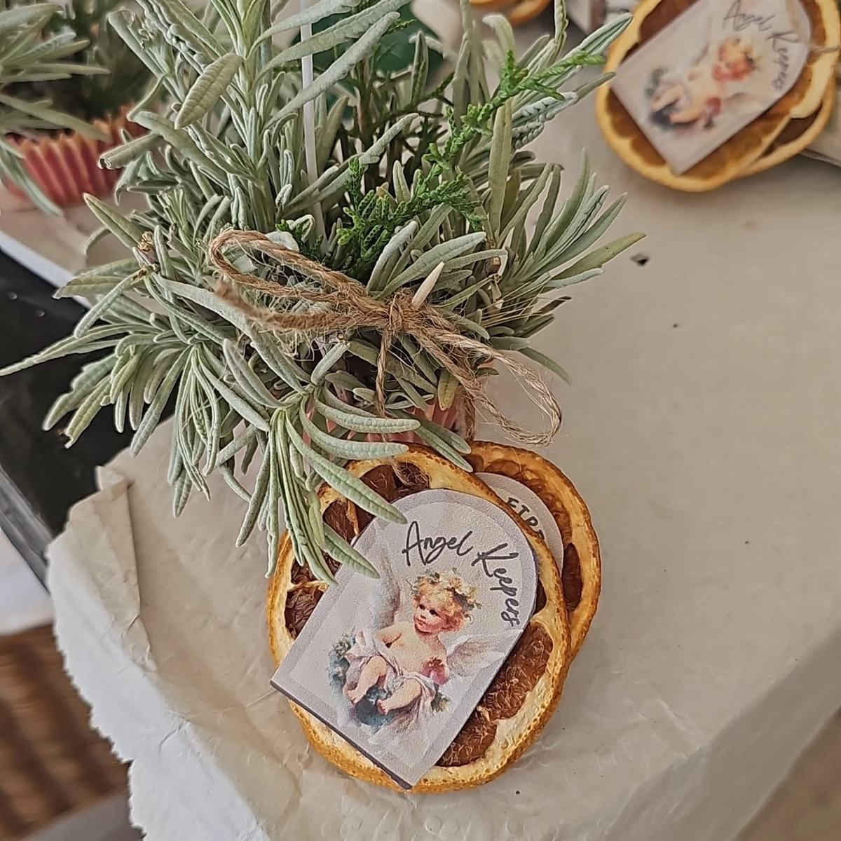 An Angel Keepers craft — dried orange slices with a lavender bundle tied with twine and a cherub tag, hand-made by Ana Sterrenberg